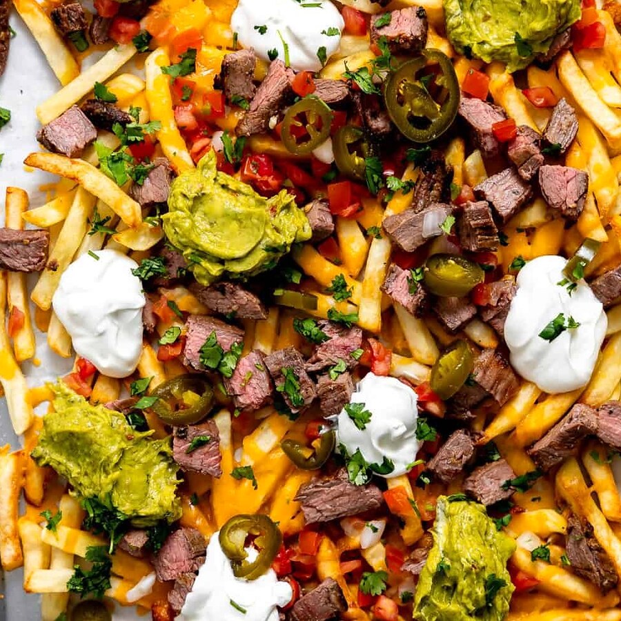 A tray of fries loaded with carne asada, melted cheese, guacamole, sour cream and pico de gallo